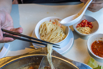 Woman hands using chopsticks while eating noodle soup