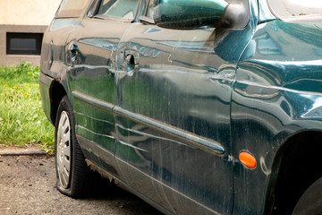 Damaged side door on a dark greencar after a traffic accident