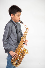 Obraz na płótnie Canvas Little asian musician boy playing saxophone instrument