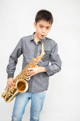 Obraz premium Little asian musician boy playing saxophone instrument