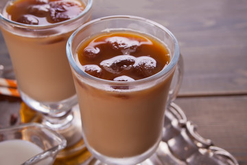 Iced latte coffee with ice cubes and coffee beans on a table.