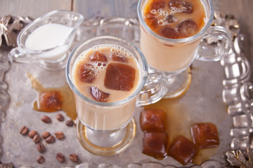 Iced latte coffee with ice cubes and coffee beans on a table.