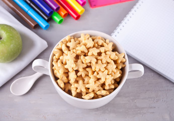 A bowl of dry stars cereal and green apple on the gray table for health breakfast