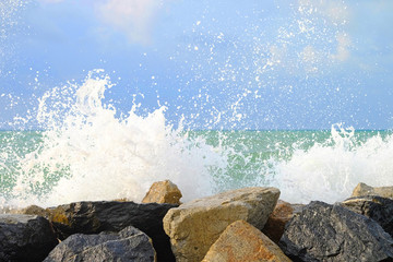 Water wave hit stone wall and made instant bubble foam on the shore