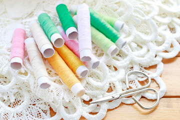 Fototapeta na wymiar Colorful threads and beautiful white french lace on wooden table.