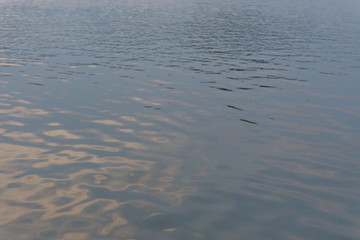 Water ripple surface reflection effect from sunset and sky top view at lake in evening day,gold wave nature abstract background
