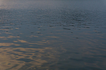 Water ripple surface reflection effect from sunset and sky top view at lake in evening day,gold wave nature abstract background