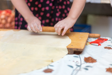 Hands working with bread dough recipe preparation. Female hands making dough. Women's hands roll out the dough. Mom rolls dough on a kitchen board with a rolling pin