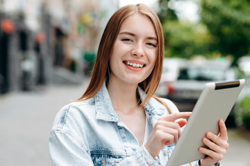 Closeup portrait of young woman holding an ipad and standing outdoor- Image