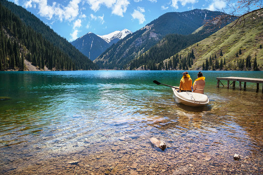 Two girls in a boat on a clear mountain lake