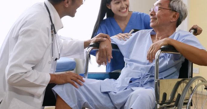 Doctor and physiotherapist talking to elderly patient sitting on wheelchair