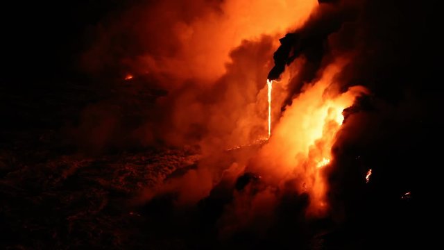 Lava reaching ocean from lava stream on Big Island Hawaii. Lava running into pacific ocean and red hot glowing lava rocks flowing out with waves. Dramatic amazing nature landscape. Volcanic eruption.