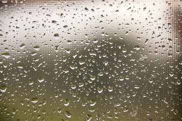 texture of rain drops on dirty window glass over blur and cloudy sunset sky background