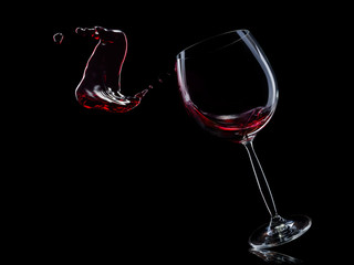 Naklejka na ściany i meble Glass for red wine with splashes isolated on black background.