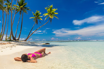 Beach suntan woman relaxing lying down on sand vacation tanning in tropical idyllic summer...