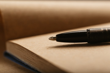Opened notepad with automatic plastic ballpoint pen close up. Toned vintage