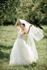 Fototapeta na wymiar bride posing in a green park; girl in a white dress on a background of green