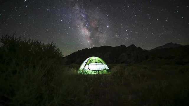 Milky Way motion timelapse with a camping tent illuminated with light. Night sky camping in Eastern Sierra Mountain wilderness
