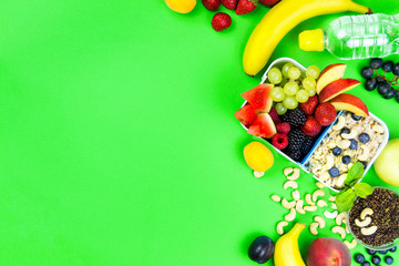 Raw healthy food: banana, berries: strawberry, blackberry, raspberry, grape with quinoa and cashew nuts for breakfast isolated on green background. Healthy, fitness, diet and raw food to go concept.