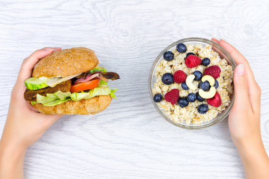 Healthy fitness low calories food: oat with raspberry, blueberry and cashew nuts compare to unhelthy fat fast food: meat burger with french fries isolated on white background. Choose lifestyle concept