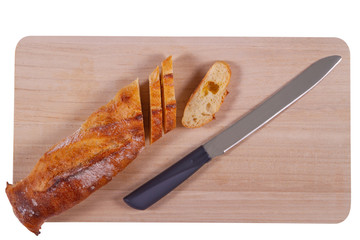 Wooden cutting board with sliced baguette and knife isolated on white background