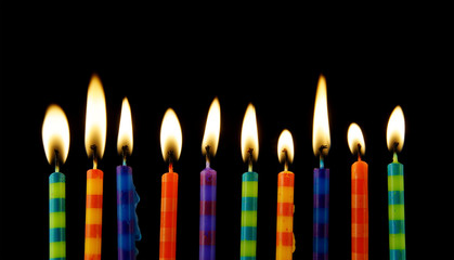 Burning colorful birthday candles on black background
