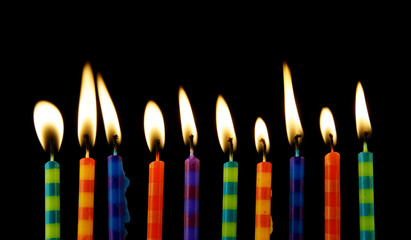 Burning birthday candles on black background