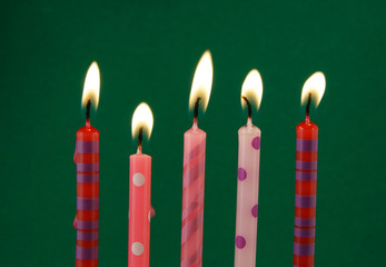 Burning birthday candles on green background