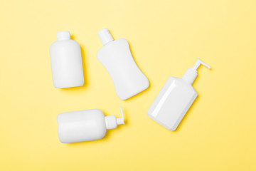 Set of White Cosmetic containers isolated on yellow background, top view with copy space. Group of plastic bodycare bottle containers with empty space for you design