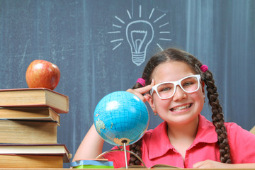 Happy school girl in front of the blackboard