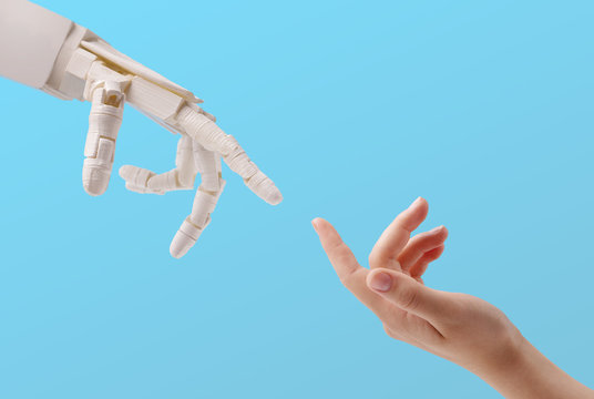 Female Hand And Robot Reaching To Each Other On Blue