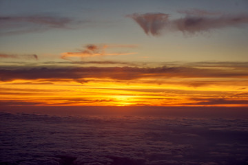 orange sky and clouds from an airplane window during an evening flight.