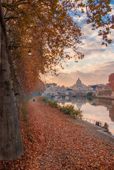 Fototapeta premium Autumn and foliage in Rome. Afternoon romantic walk along River Tiber with red and yellow leaves, in the city historic center