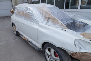 The car after the accident in the workshop for body repair is partially covered with paper and...