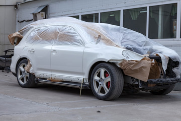 The car after the accident in the workshop for body repair is partially covered with paper and...