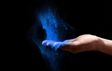 Fototapeta na wymiar Woman Hand holding blue holi powder over black background