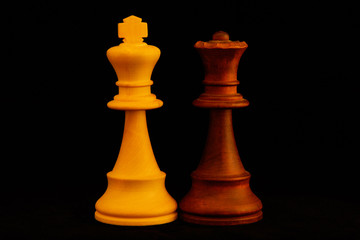 White King, Black Queen as mixed couple concept.Standard chess wooden pieces on black background