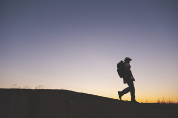 Naklejka na ściany i meble backpacker traveler walking at sunrise