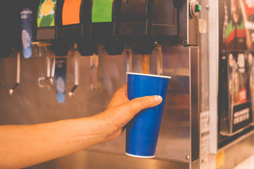 hand holding a paper glass to pour the lemonade soda soft drink  machine  in a fastfood restaurant - Powered by Adobe
