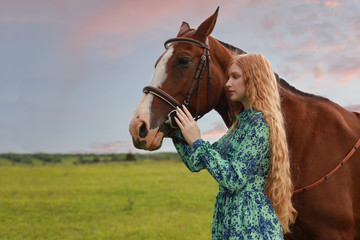 Fototapeta premium orange hair woman and her brown horse in the field just relaxing in summer day