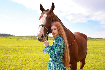 Obraz premium Portrait of young smiling beautiful woman walking with brown horse outdoors