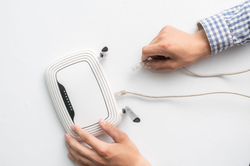 hand conncecting the ethernet wire cable with wi-fi remote point
