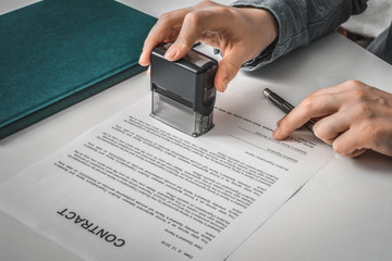 Business woman putting stamp on documents in the office