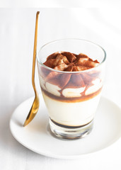Classic tiramisu cake in a glass on white background. Layered mascarpone dessert cake. ..