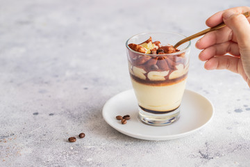 Classic tiramisu cake in a glass on concrete background. Layered mascarpone dessert cake.