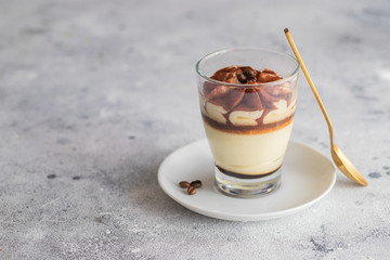 Classic tiramisu cake in a glass on concrete background. Layered mascarpone dessert cake.