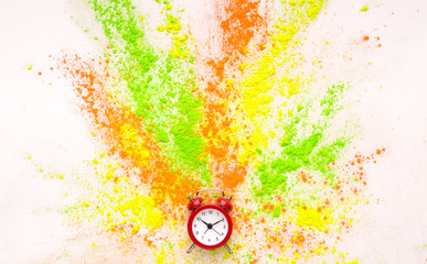 Coloured holi powder explosion out of alarm clock on white