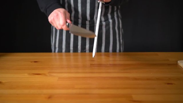Slow motion of a man Chef using various techniques to sharpen a knife with his hands, using a professional knife and a diamond sharpening steel.