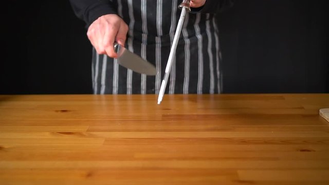 Slow motion of a man Chef using various techniques to sharpen a knife with his hands, using a professional knife and a diamond sharpening steel.