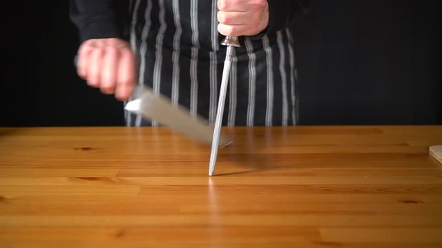 Slow motion of a man Chef using various techniques to sharpen a knife with his hands, using a professional knife and a diamond sharpening steel.
